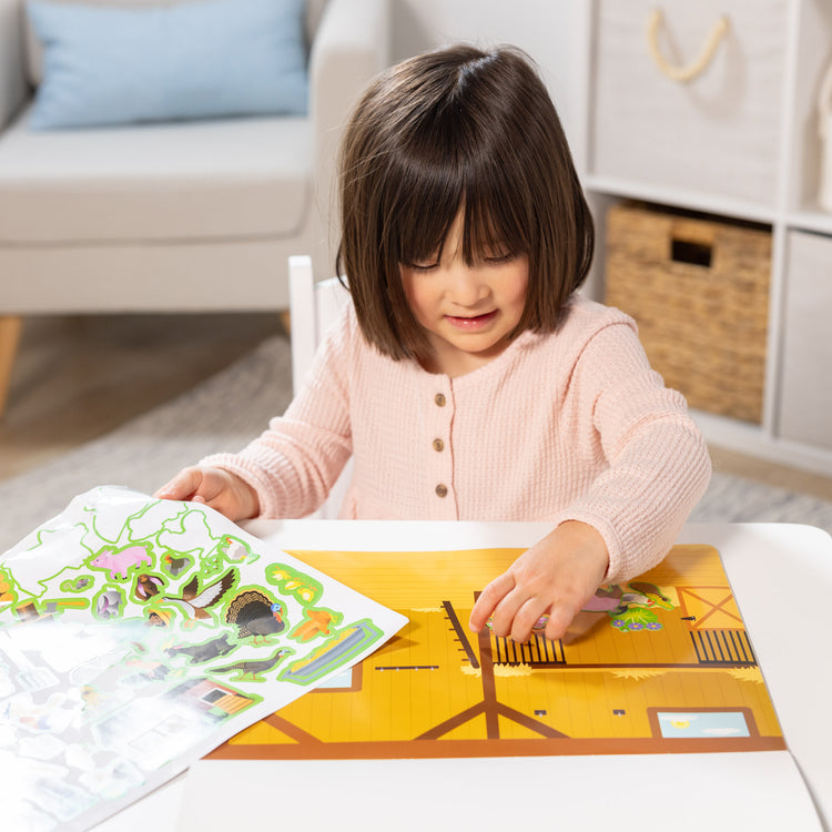 A kid playing with The Melissa & Doug Reusable Sticker Pad: Farm - 280+ Stickers, 5 Scenes