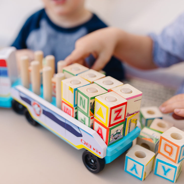 A kid playing with The Melissa & Doug PAW Patrol Wooden ABC Block Truck (33 Pieces)