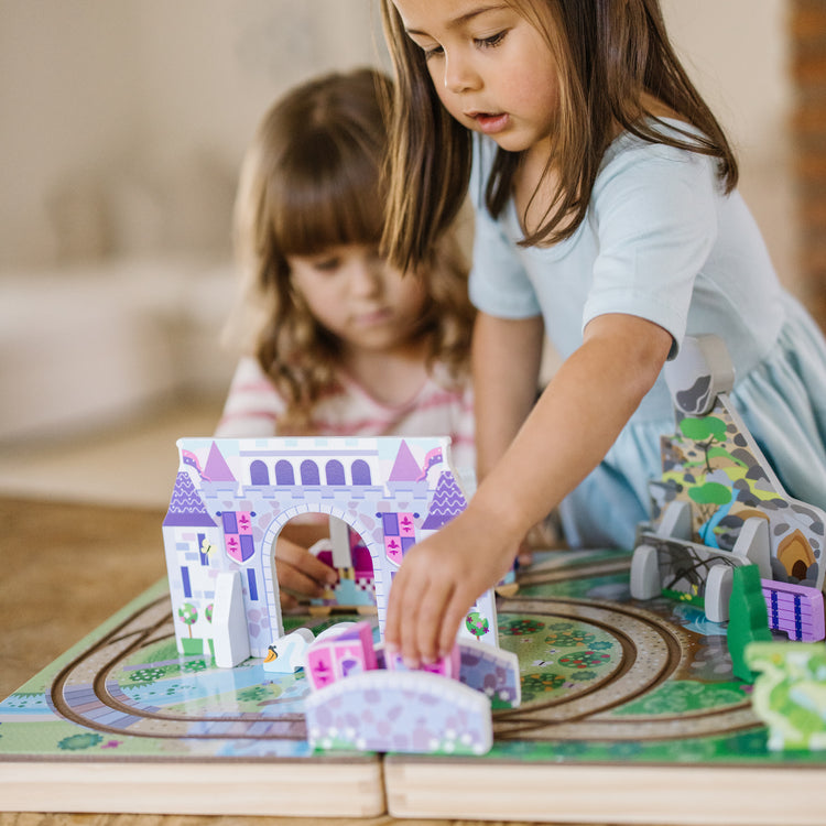 A kid playing with The Melissa & Doug 19-Piece Wooden Take-Along Tabletop Kingdom – Carriage, Horse, Unicorn, Dragon, More