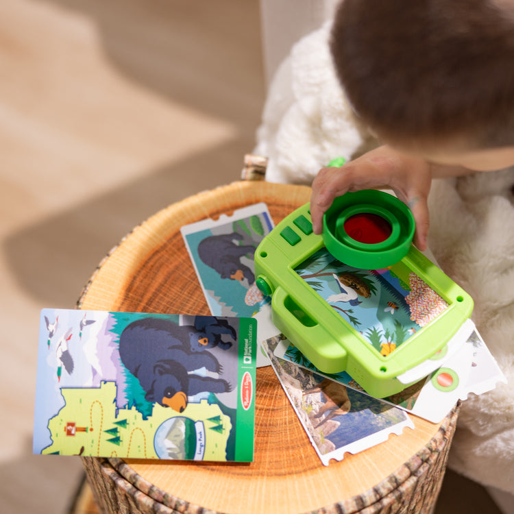 A kid playing with The Melissa & Doug Rocky Mountain National Park Sights and Sounds Wooden Toy Camera Play Set