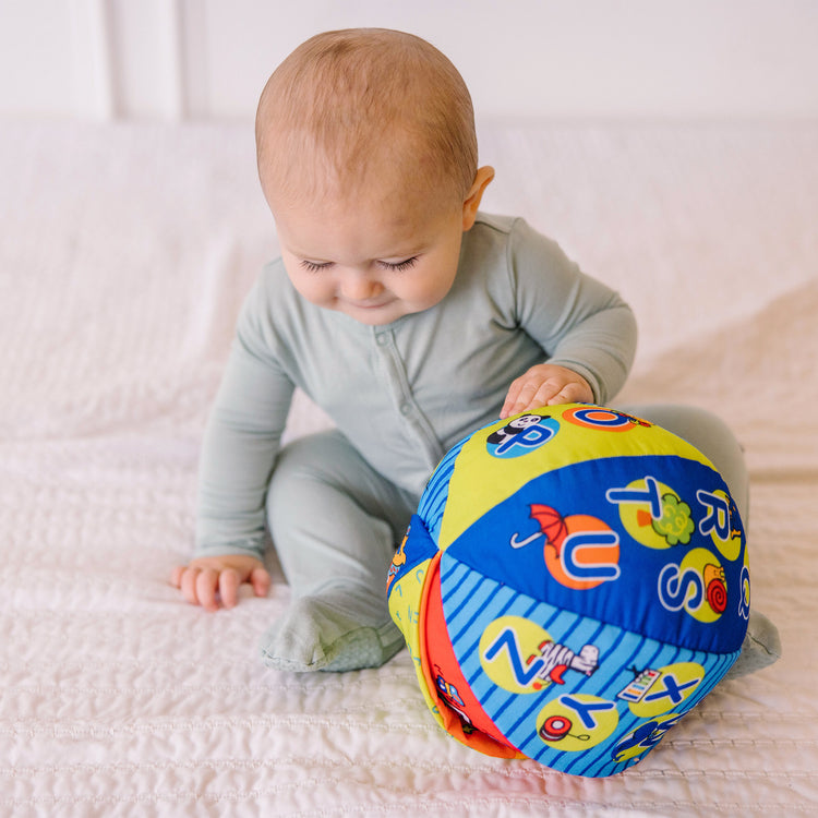 A kid playing with The Melissa & Doug K's Kids 2-in-1 Talking Ball Educational Toy - ABCs and Counting 1-10