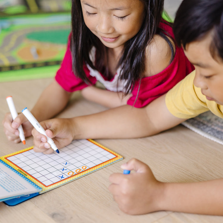 A kid playing with The Melissa & Doug On the Go Game On! Reusable Games Wipe-Off Activity Pad Reusable Travel Toy with 2 Dry-Erase Markers