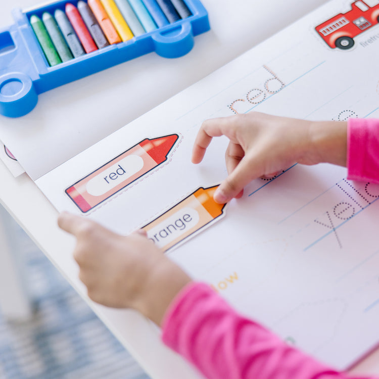 A kid playing with The Melissa & Doug Colors and Shapes Coloring and Sticker Activity Pad