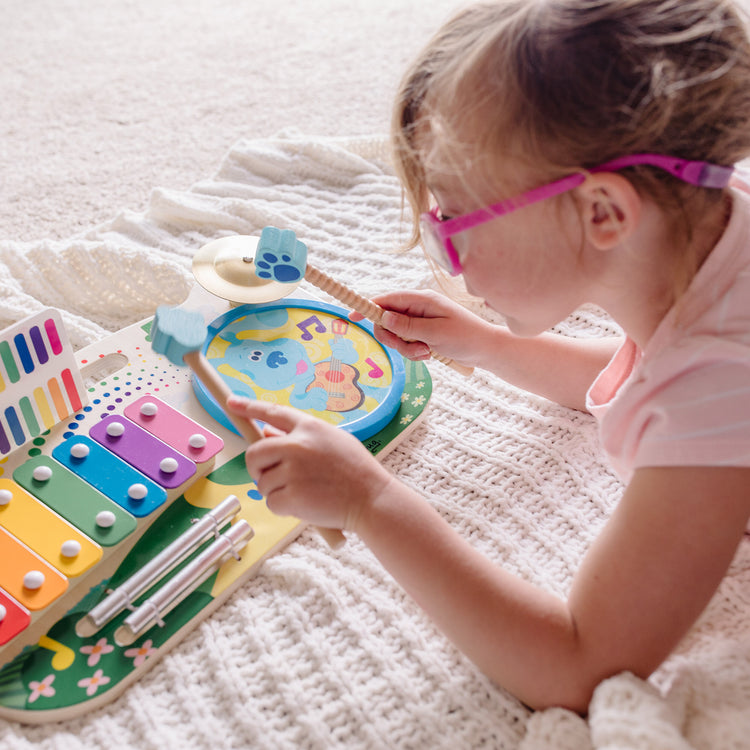 A kid playing with The Melissa & Doug Blue's Clues & You! Wooden Music Maker Board (5 Instruments)