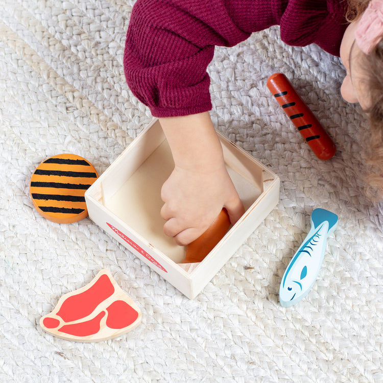 A kid playing with The Melissa & Doug Wooden Food Groups Play Food Set – Protein