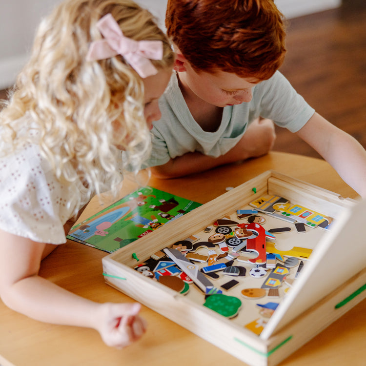 A kid playing with The Melissa & Doug Wooden Magnetic Matching Picture Game With 119 Magnets and Scene Cards