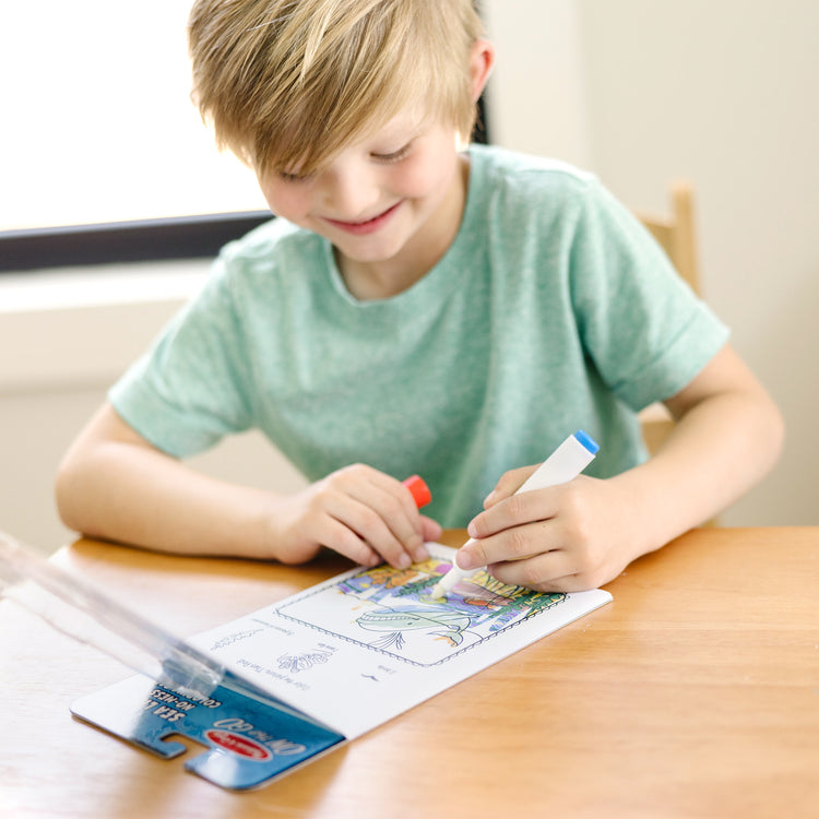 A kid playing with The Melissa & Doug On the Go ColorBlast! Activity Book: Sea Life - 24 Pictures and No-Mess Pen