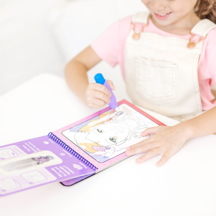 A kid playing with The Melissa & Doug On the Go Water Wow! Reusable Water-Reveal Activity Pad - Makeup and Manicures