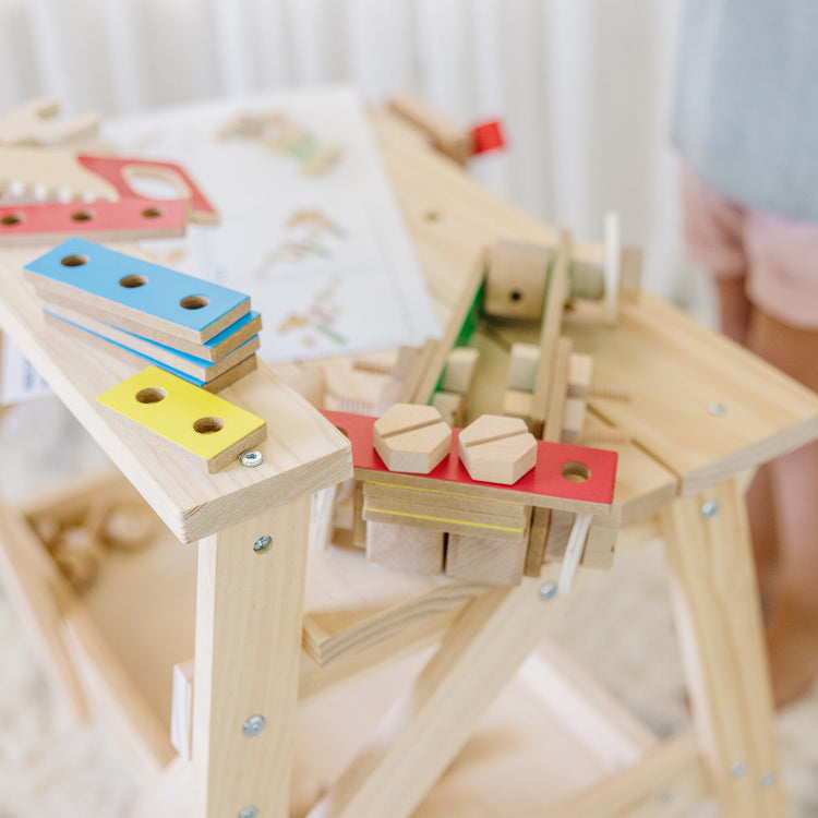 A kid playing with The Melissa & Doug Solid Wood Project Workbench Play Building Set