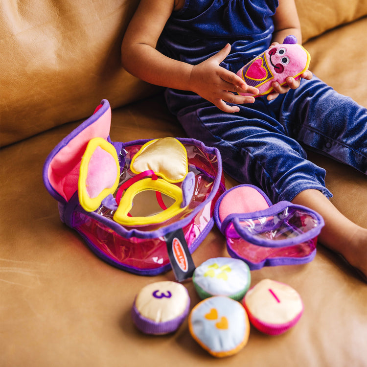 A kid playing with The Melissa & Doug Pretty Purse Fill and Spill Soft Play Set Toddler Toy