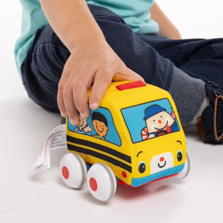 A kid playing with The Melissa & Doug K's Kids Pull-Back Vehicle Set - Soft Baby Toy Set With 4 Cars and Trucks and Carrying Case