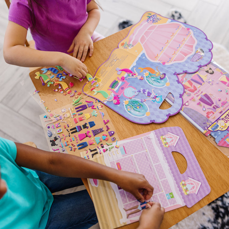 A kid playing with The Melissa & Doug Puffy Sticker Activity Books Set: Dress-Up, Princess, Mermaid - 208 Reusable Stickers