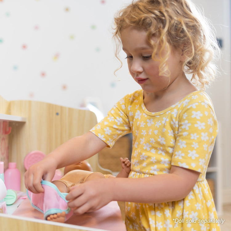 A kid playing with The Melissa & Doug Baby Care Center and Accessory Sets