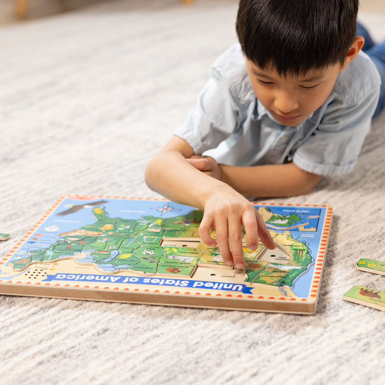 A kid playing with The Melissa & Doug USA Map Sound Puzzle - Wooden Puzzle With Sound Effects (40 pcs), Multicolor