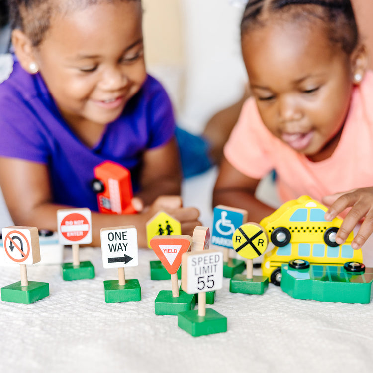 A kid playing with The Melissa & Doug Wooden Vehicles and Traffic Signs With 6 Cars and 9 Signs