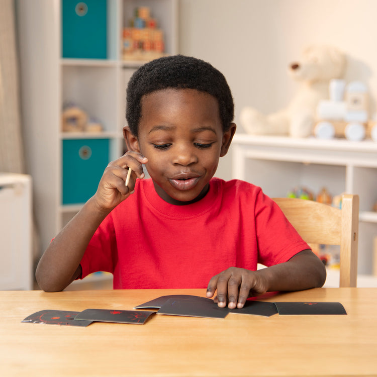 A kid playing with The Melissa & Doug Scratch Art Rainbow Mini Notes (125) With Wooden Stylus