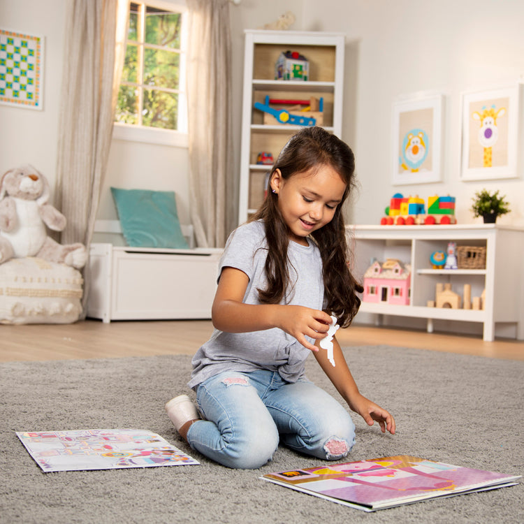 A kid playing with The Melissa & Doug Reusable Sticker Pad: Princess Castle - 200+ Stickers and 5 Scenes