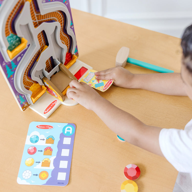 A kid playing with The Melissa & Doug Fun at the Fair! Wooden Ring the Bell Game