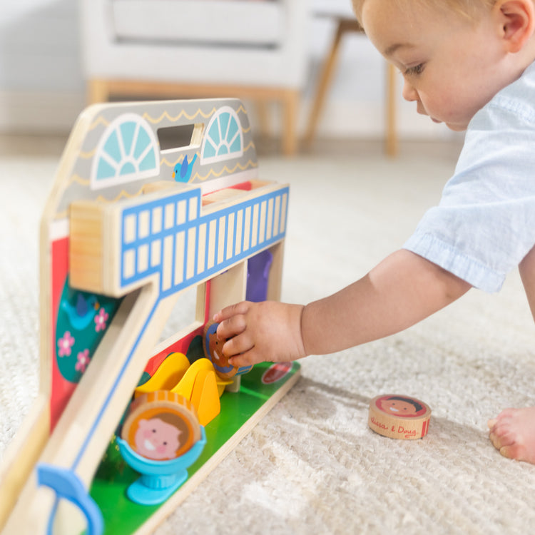 A kid playing with The Melissa & Doug GO Tots Wooden Schoolyard Tumble with 4 Disks