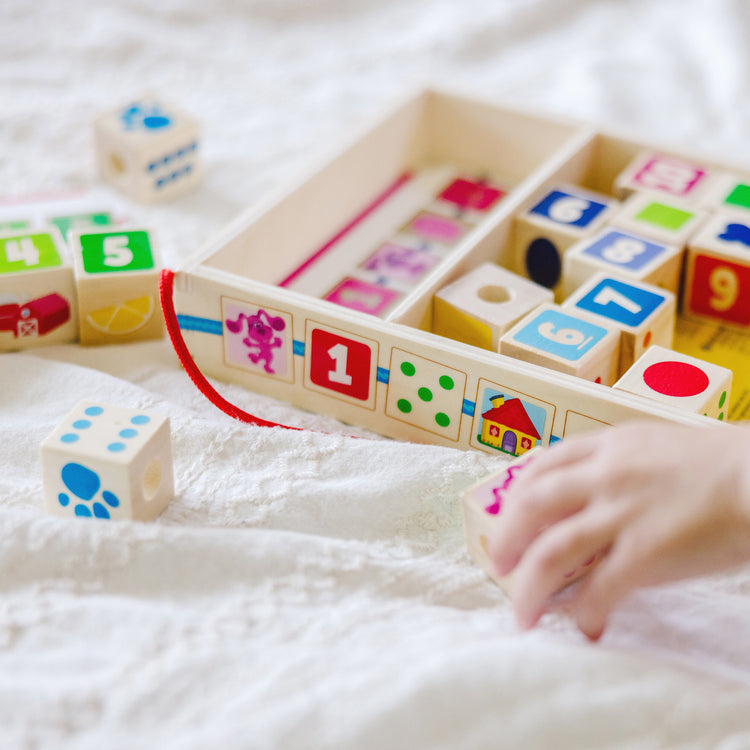 A kid playing with The Melissa & Doug Blue’s Clues & You! Wooden Lacing Beads - 25 Beads, 4 Cords