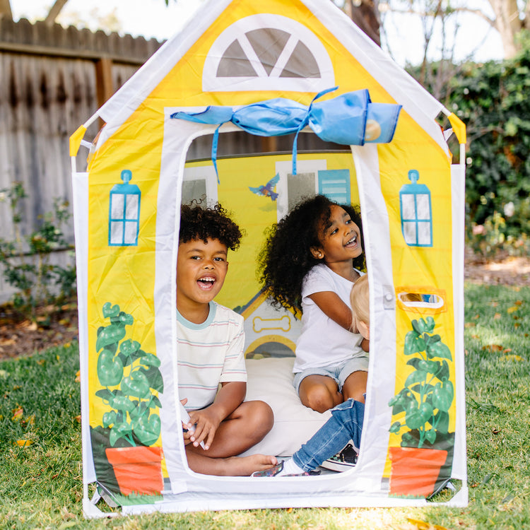 A kid playing with The Melissa & Doug Cozy Cottage Fabric Play Tent and Storage Tote