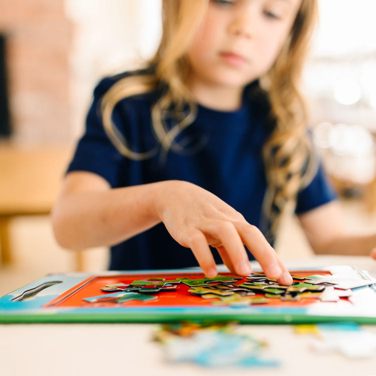 A kid playing with The Melissa & Doug Take-Along Magnetic Jigsaw Puzzles Travel Toy On the Farm (2 15-Piece Puzzles)