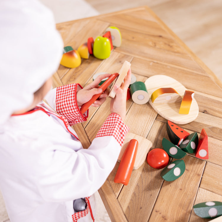 A kid playing with The Melissa & Doug Chef Role Play Costume Dress -Up Set With Realistic Accessories