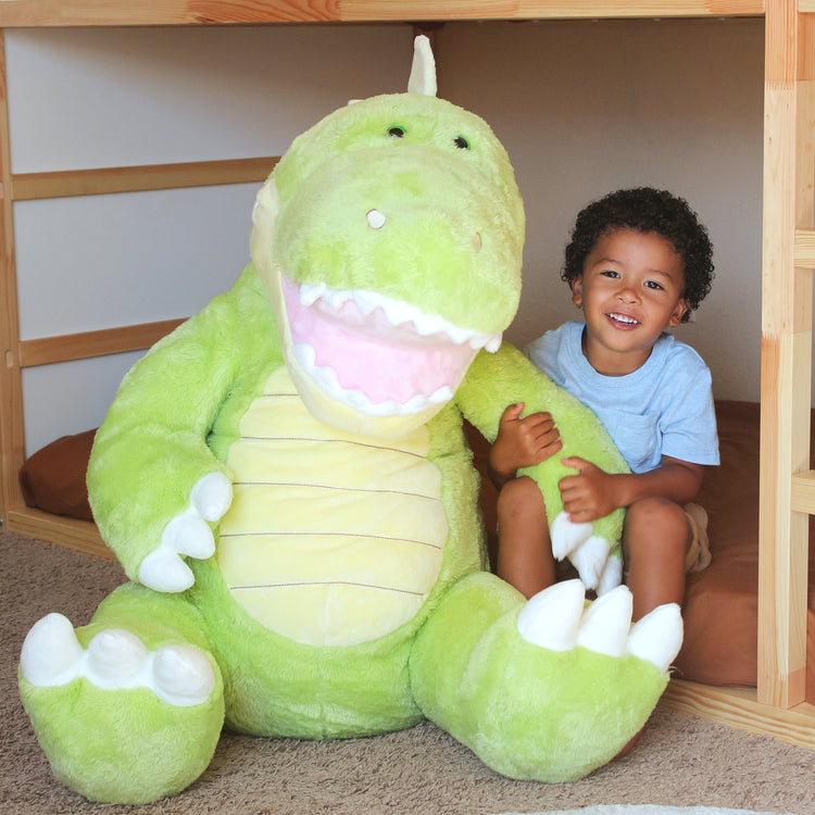 A kid playing with The Melissa & Doug Gentle Jumbos Dinosaur Giant Stuffed Plush Animal (Sits Nearly 3 Feet Tall)