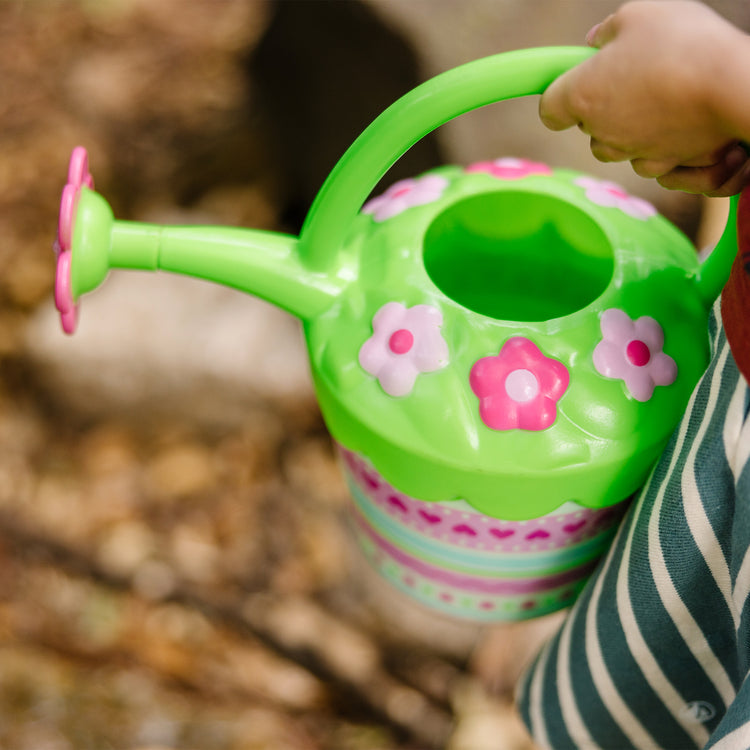 A kid playing with The Melissa & Doug Sunny Patch Pretty Petals Flower Watering Can - Pretend Play Toy