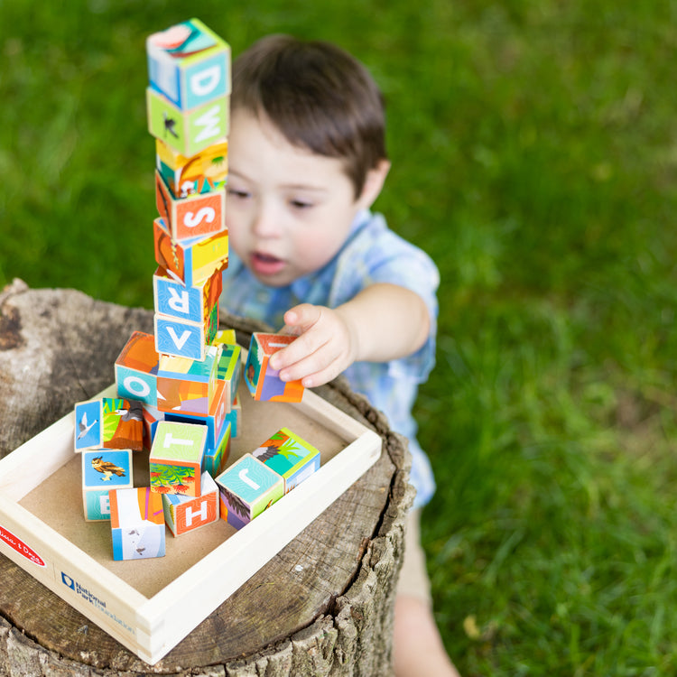 A kid playing with The Melissa & Doug National Parks Alphabet & Animals 24-Piece Cube Puzzle (Everglades, Arches, Yellowstone)