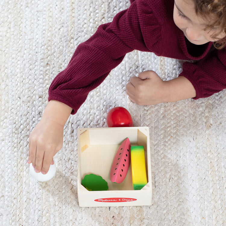 A kid playing with The Melissa & Doug Wooden Food Groups Play Food Set – Produce