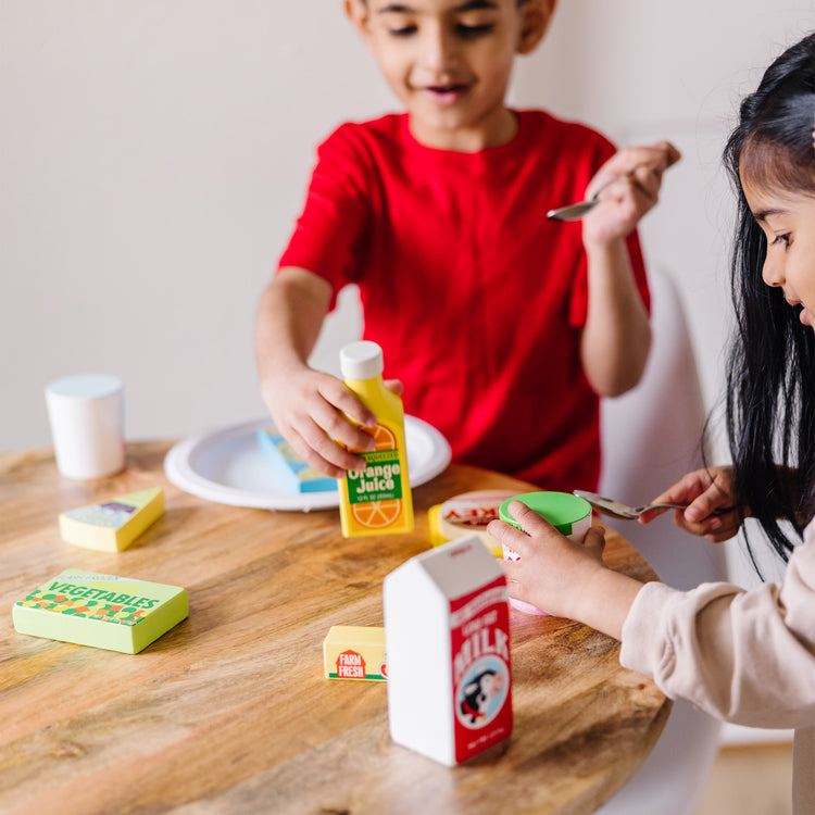 A kid playing with The Melissa & Doug Fridge Food Wooden Play Food Set - 9 Pieces