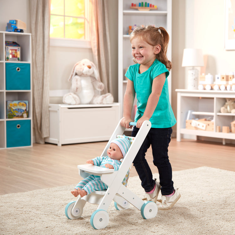 A kid playing with The Melissa & Doug Mine to Love Wooden Play Stroller for Dolls, Stuffed Animals - White (18”H x 8”W x 11”D Assembled)