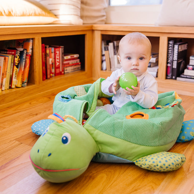 A kid playing with The Melissa & Doug K's Kids Turtle Ball Pit With 60 Balls