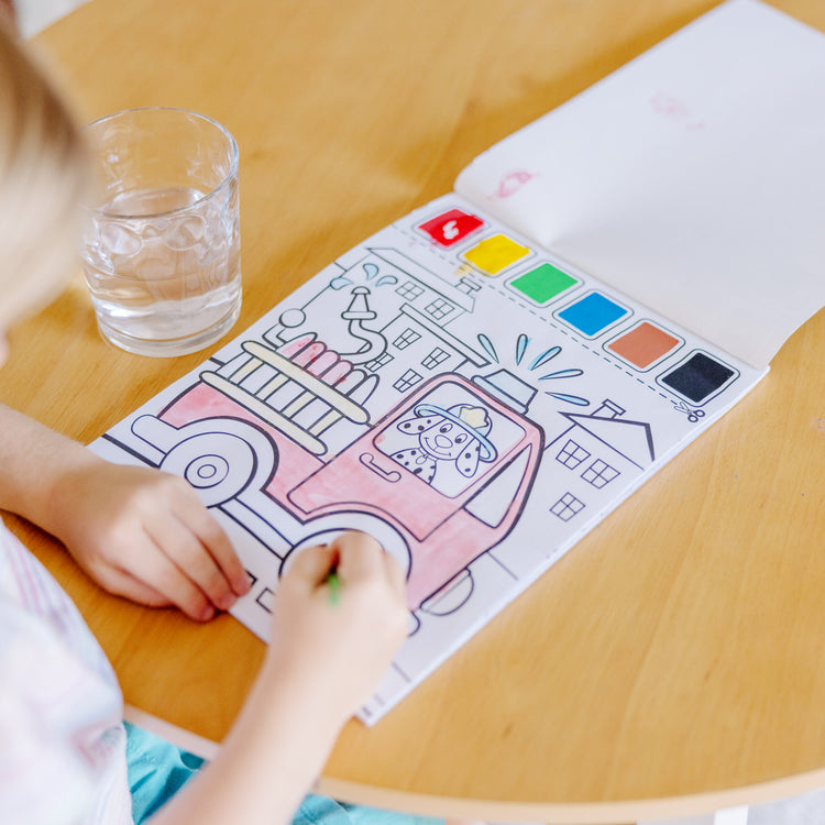 A kid playing with The Melissa & Doug Paint With Water - Vehicles, 20 Perforated Pages With Spillproof Palettes