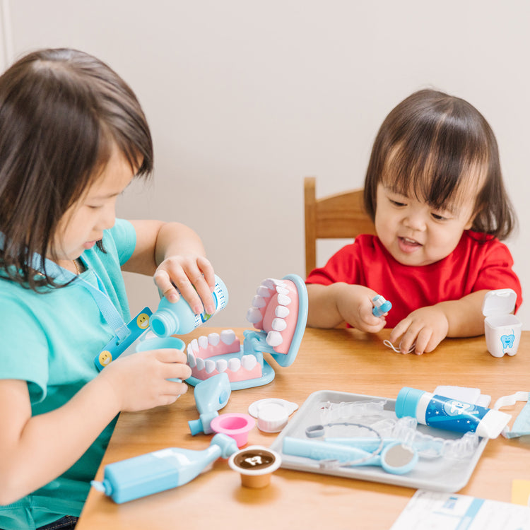 A kid playing with The Melissa & Doug Super Smile Dentist Kit With Pretend Play Set of Teeth And Dental Accessories (25 Toy Pieces)