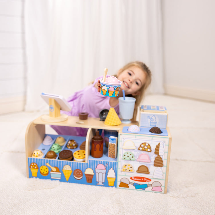 A kid playing with The Melissa & Doug Wooden Cool Scoops Ice Creamery Play Food Toy