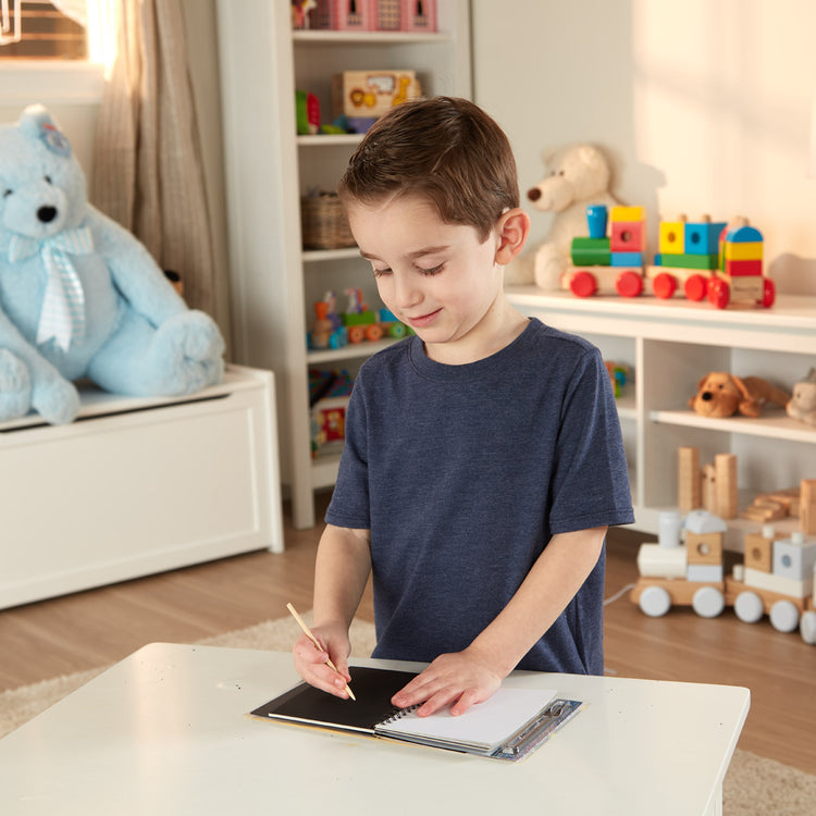 A kid playing with The Melissa & Doug Scratch Art Doodle Pad With 16 Scratch-Art Boards and Wooden Stylus