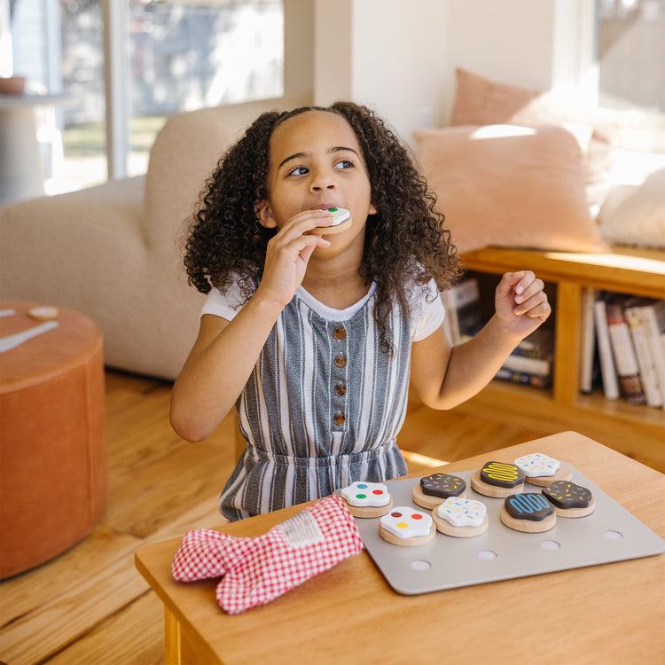 A kid playing with The Melissa & Doug Slice and Bake Wooden Cookie Play Food Set