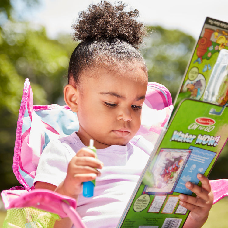 A kid playing with The Melissa & Doug On the Go Water Wow! Reusable Water-Reveal Activity Pad - Animals