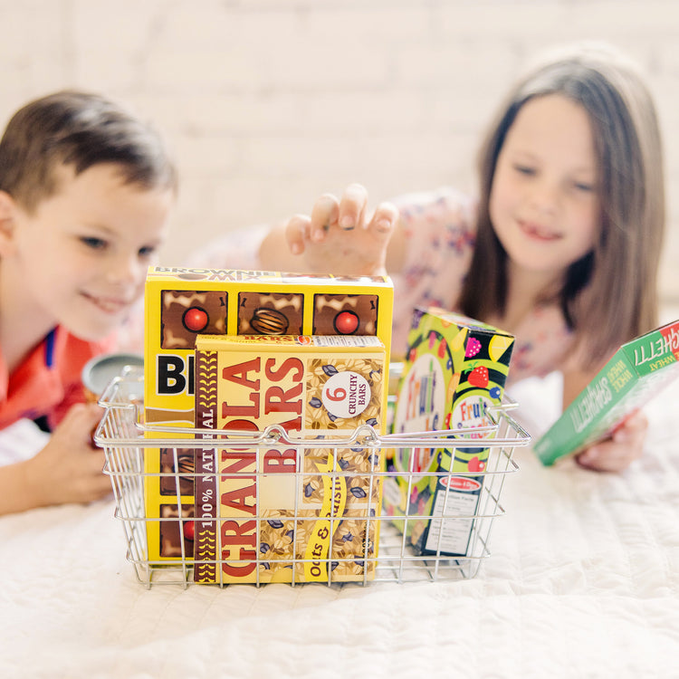 A kid playing with The Melissa & Doug Grocery Basket - Pretend Play Toy With Heavy Gauge Steel Construction