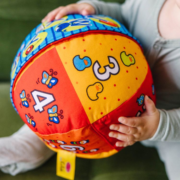 A kid playing with The Melissa & Doug K's Kids 2-in-1 Talking Ball Educational Toy - ABCs and Counting 1-10