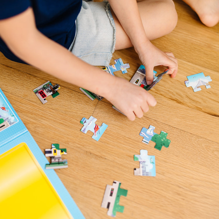 A kid playing with The Melissa & Doug Take-Along Magnetic Jigsaw Puzzles Travel Toy – Vehicles (2 15-Piece Puzzles)