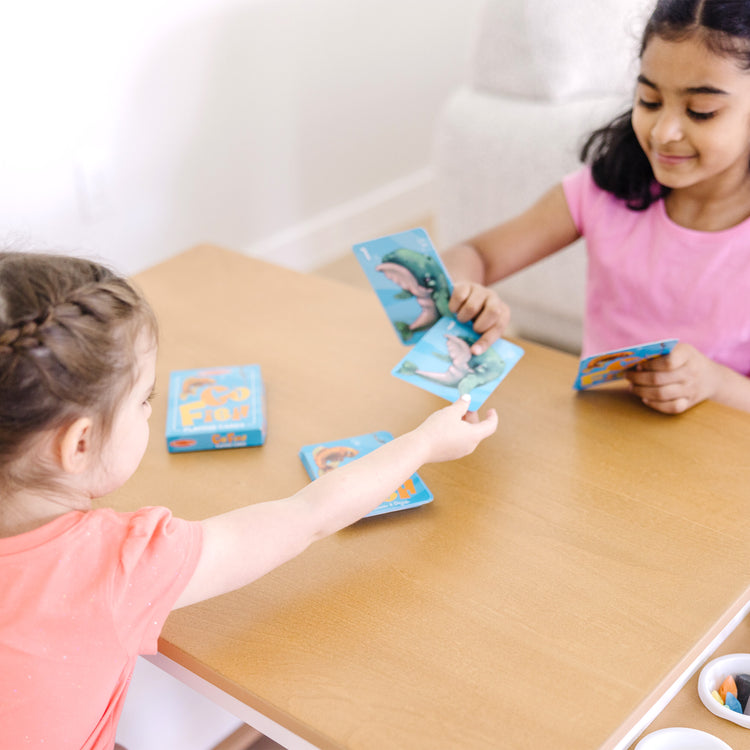 A kid playing with The Melissa & Doug Classic Card Games Set - Old Maid, Go Fish, Rummy