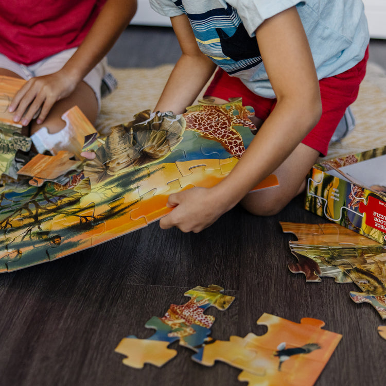 A kid playing with The Melissa & Doug African Plains Safari Jumbo Jigsaw Floor Puzzle (100 pcs, over 4 feet long)