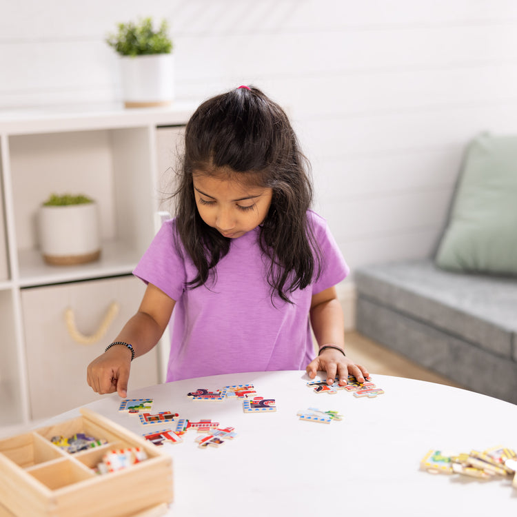 A kid playing with The Melissa & Doug Vehicles 4-in-1 Wooden Jigsaw Puzzles in a Storage Box (48 pcs)