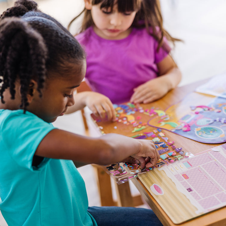 A kid playing with The Melissa & Doug Puffy Sticker Activity Books Set: Dress-Up, Princess, Mermaid - 208 Reusable Stickers