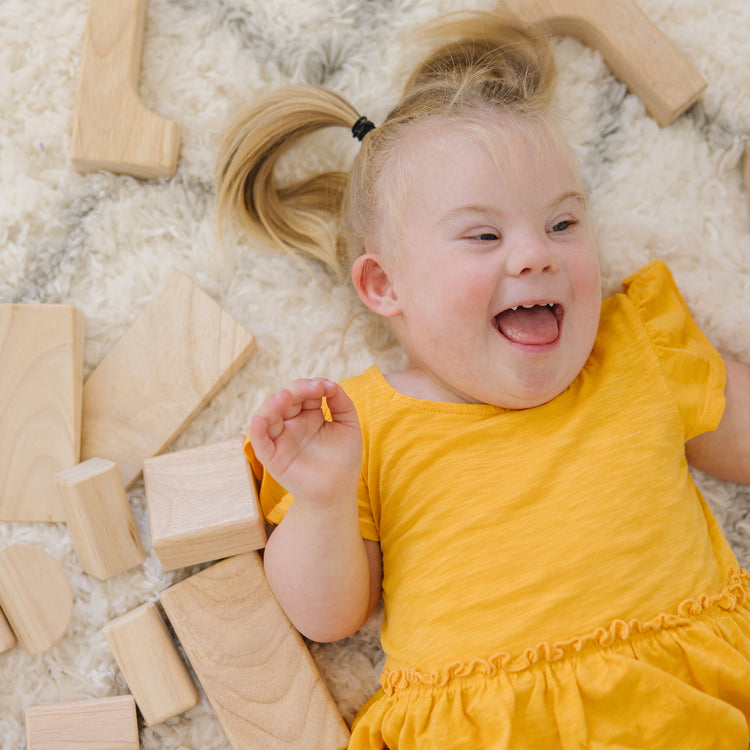 A kid playing with The Melissa & Doug Standard Unit Solid-Wood Building Blocks With Wooden Storage Tray (60 pcs)