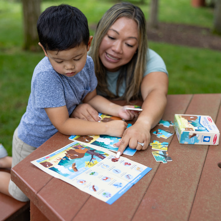 A kid playing with The Melissa & Doug Yellowstone National Park Wooden Jigsaw Puzzle – 24 Pieces, Animal and Plant ID Guide