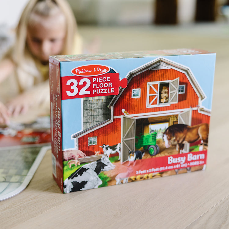 A kid playing with The Melissa & Doug Busy Barn Shaped Jumbo Jigsaw Floor Puzzle (32 pcs, 2 x 3 feet)